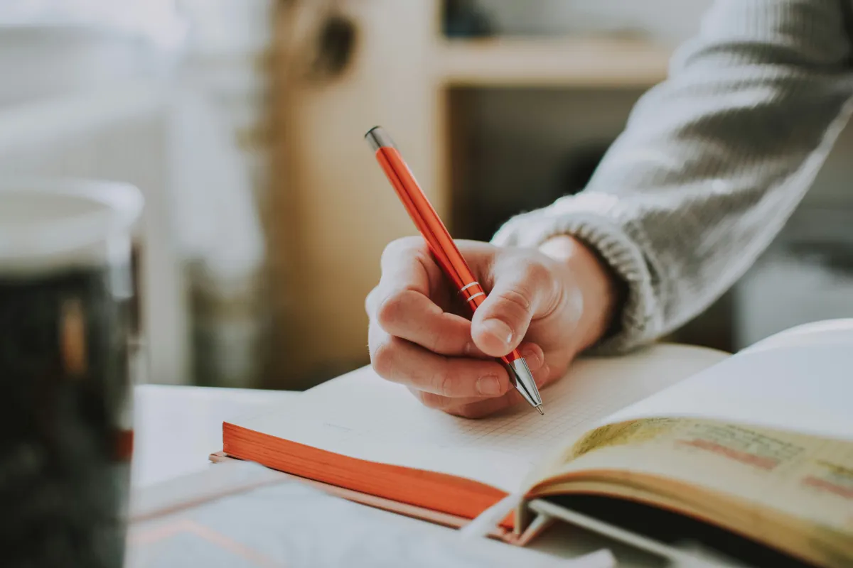 Student writing in a clean notebook with focus