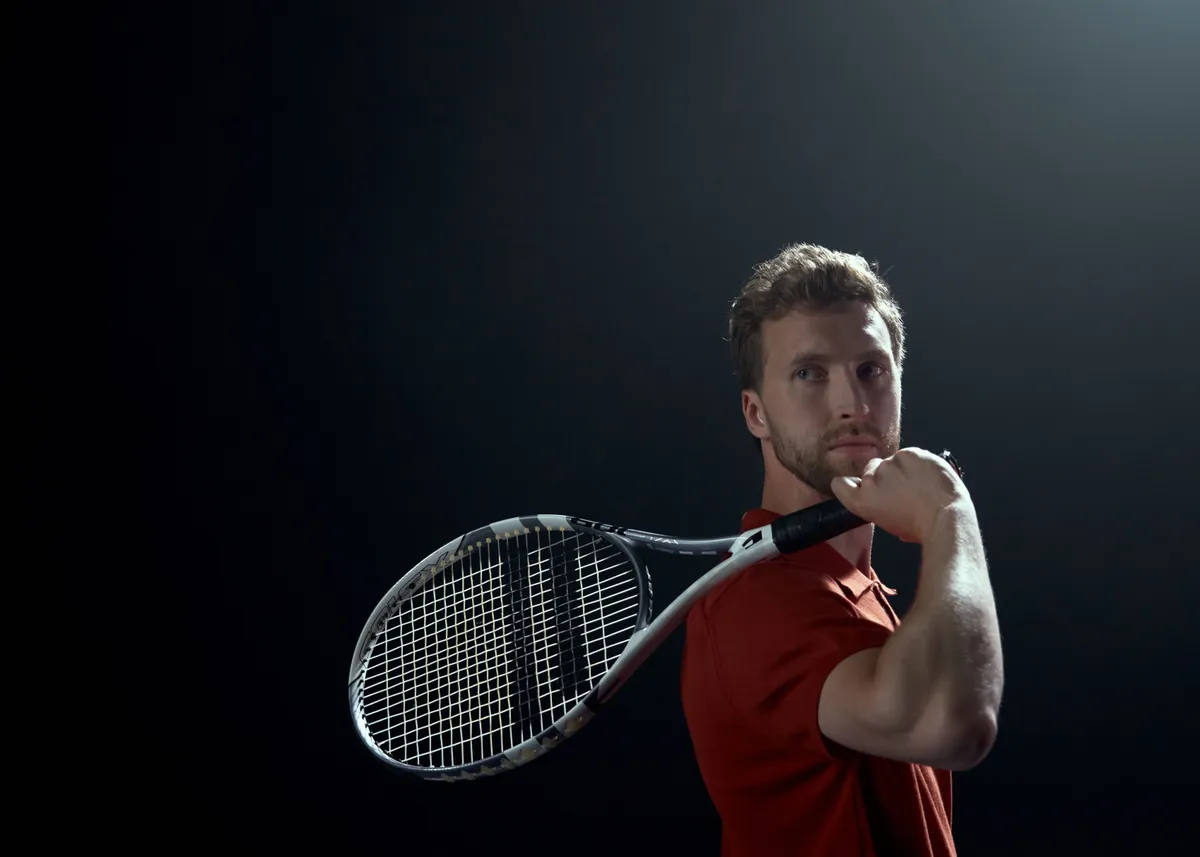 Coach BigJamo holding a tennis racket with professional focus