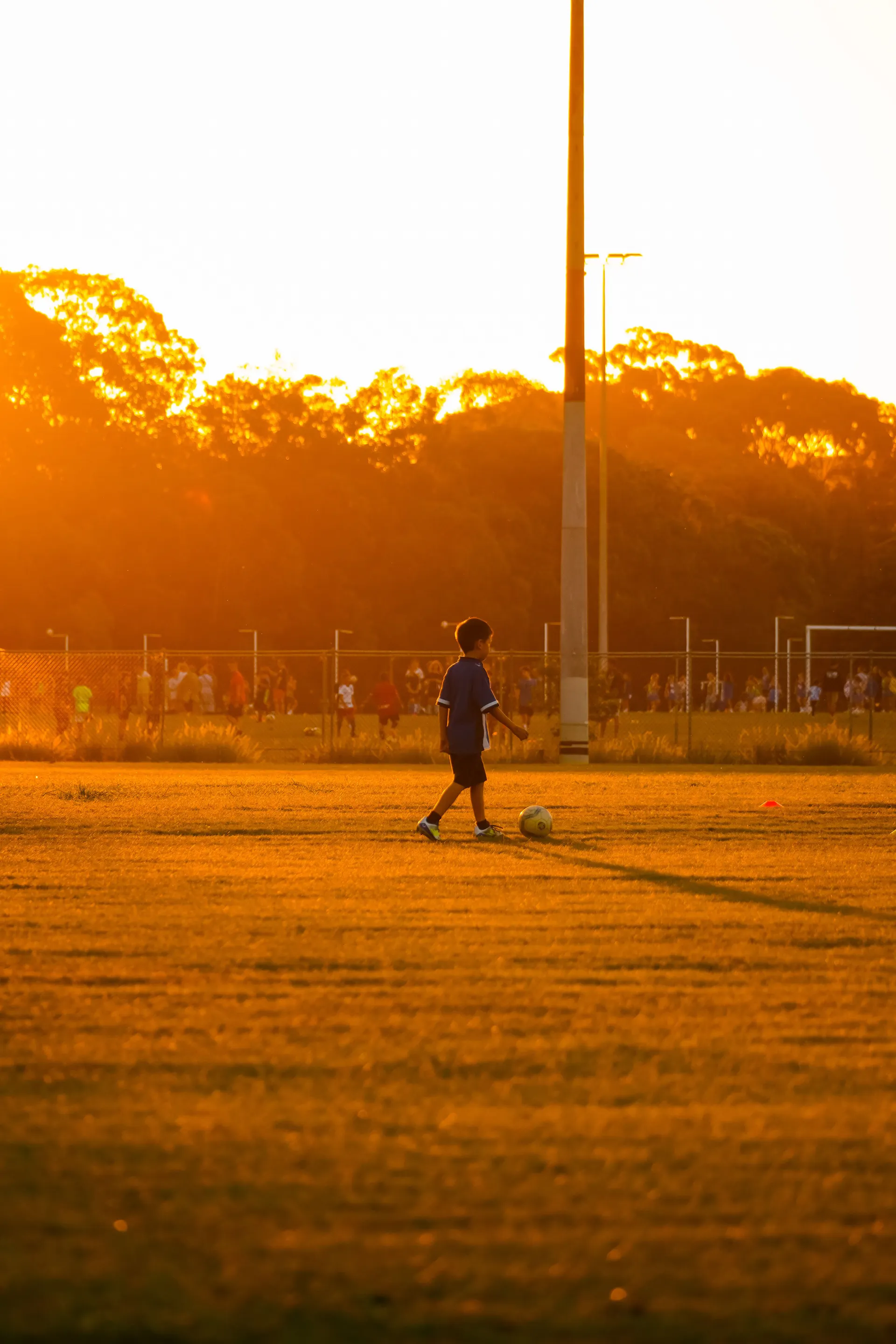 Child in soccer gear playing at sunset
