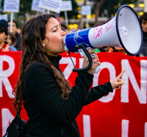 a woman speaking into a megaphone in front of a crowd
