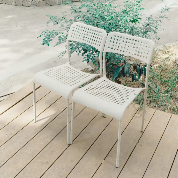 Two white chairs on a wooden deck