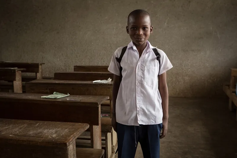 Happy pupil in royal blue uniform smiling in a classroom