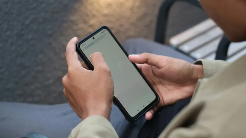 Person using cell phone on bench