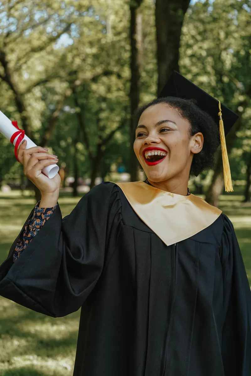 Happy graduate celebrating in outdoor setting with diploma and cap