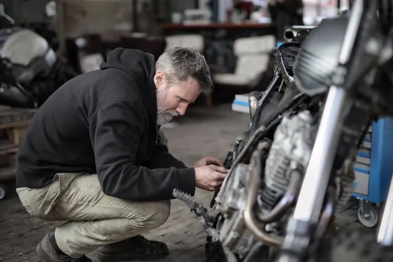 Professional mechanic inspecting a delivery motorbike