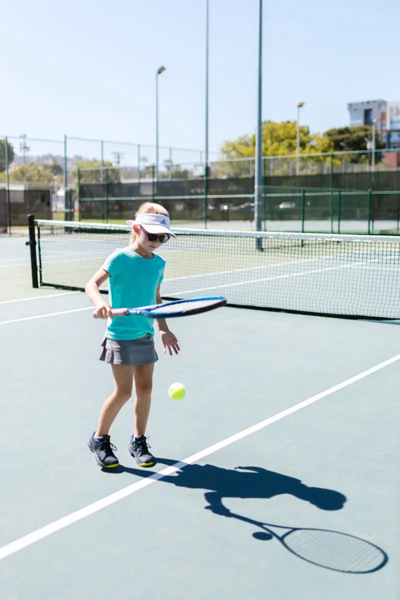 Child practicing tennis outdoors