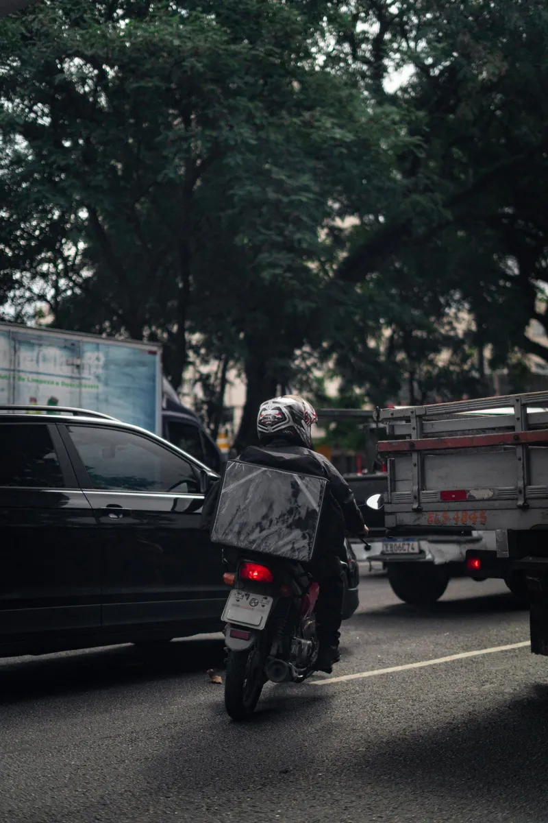A motorcyclist riding through city traffic, showcasing urban commuting challenges.